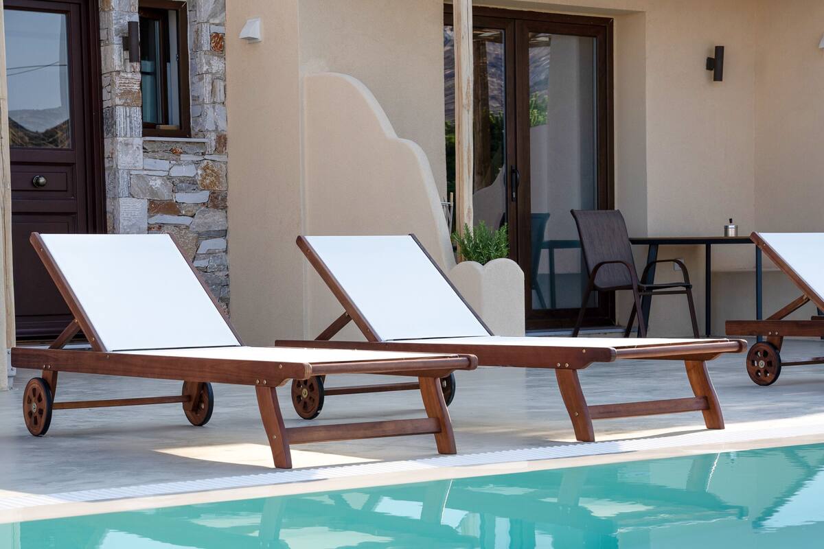 Un espace aménagé au bord de la piscine, avec des chaises longues et une table.