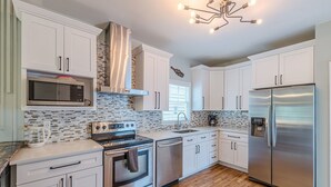 A modern kitchen with white cabinets, stainless steel appliances, and a tiled backsplash.