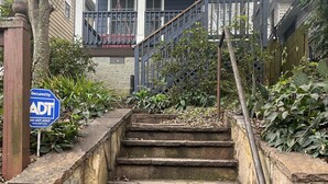 A set of stone steps leading up to a porch with a blue sign indicating security by ADT.