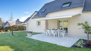 A modern house with a patio, white furniture, and a small garden.