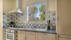 A kitchen with a window, a stove, a sink, and cabinets.