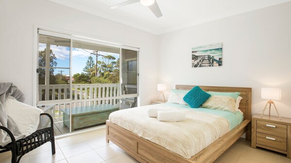 Une chambre à coucher comprenant un lit, des tables de chevet, une chaise, un balcon et une vue sur l’extérieur.