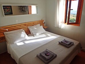 A bed with a wooden headboard, white bedding, and two towels on the bed.