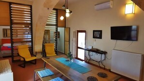 A compact living space with a bed, a desk, a chair, and a TV. - Crete, 2 houses together for 2 families (kefalas)