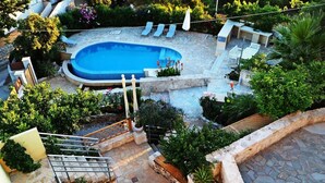 A rooftop pool area with a glass balustrade, lounge chairs, and a stone-tiled deck. - Crete, 2 houses together for 2 families (kefalas)