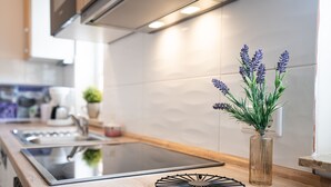 A modern kitchen with a wooden countertop, a built-in stove, and a vase with lavender plants.