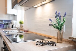 Una cocina moderna con encimera de madera, estufa integrada y un florero con plantas de lavanda.