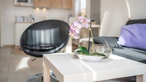 A modern living room with a white coffee table, a black chair, and a sofa with a purple cushion.