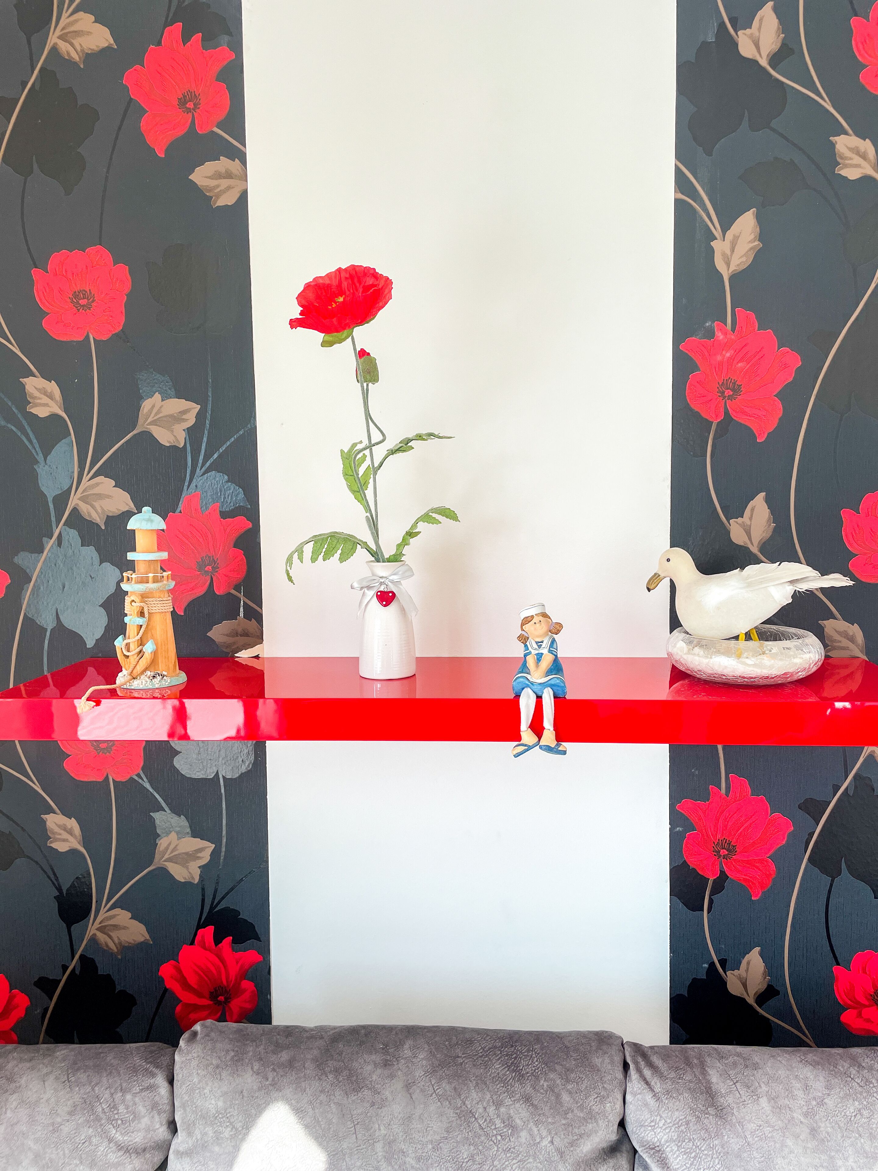 A shelf with a red vase, a white vase, and a figurine.