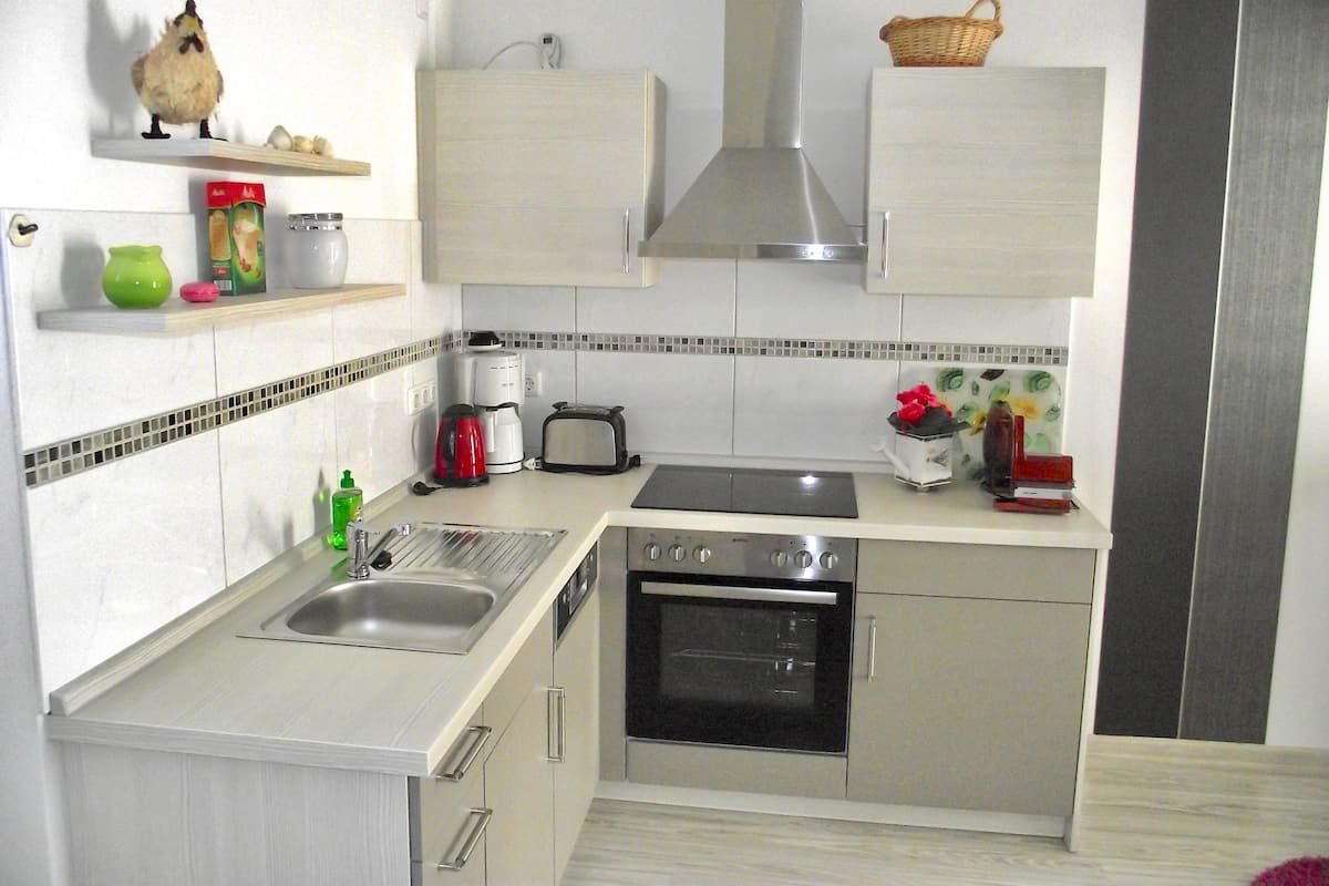 A compact kitchen with a sink, stove, oven, and a toaster.