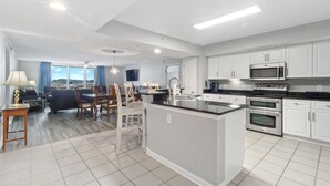 Una cocina moderna con armarios blancos, una isla central y electrodomésticos integrados.