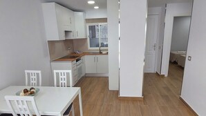 A modern kitchen with white cabinets, a wooden countertop, and a dining area with a white table and chairs. - Los Gigantes NEW apartment , 2 bedrooms (Acantilados de Los Gigantes)