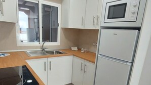 A modern kitchen with white cabinets, a stainless steel sink, a microwave, and a built-in oven. - Los Gigantes NEW apartment , 2 bedrooms (Acantilados de Los Gigantes)