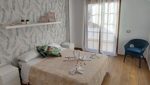 A bedroom with a bed, a nightstand, a chair, a window with curtains, and a wall with a leaf pattern. - Los Gigantes NEW apartment , 2 bedrooms (Acantilados de Los Gigantes)