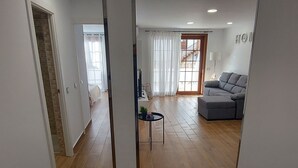 A modern living room with a grey sofa, a small round table, and a staircase leading to another level. - Los Gigantes NEW apartment , 2 bedrooms (Acantilados de Los Gigantes)