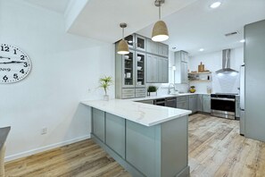 Una cocina moderna con gabinetes grises, una isla blanca y electrodomésticos de acero inoxidable.