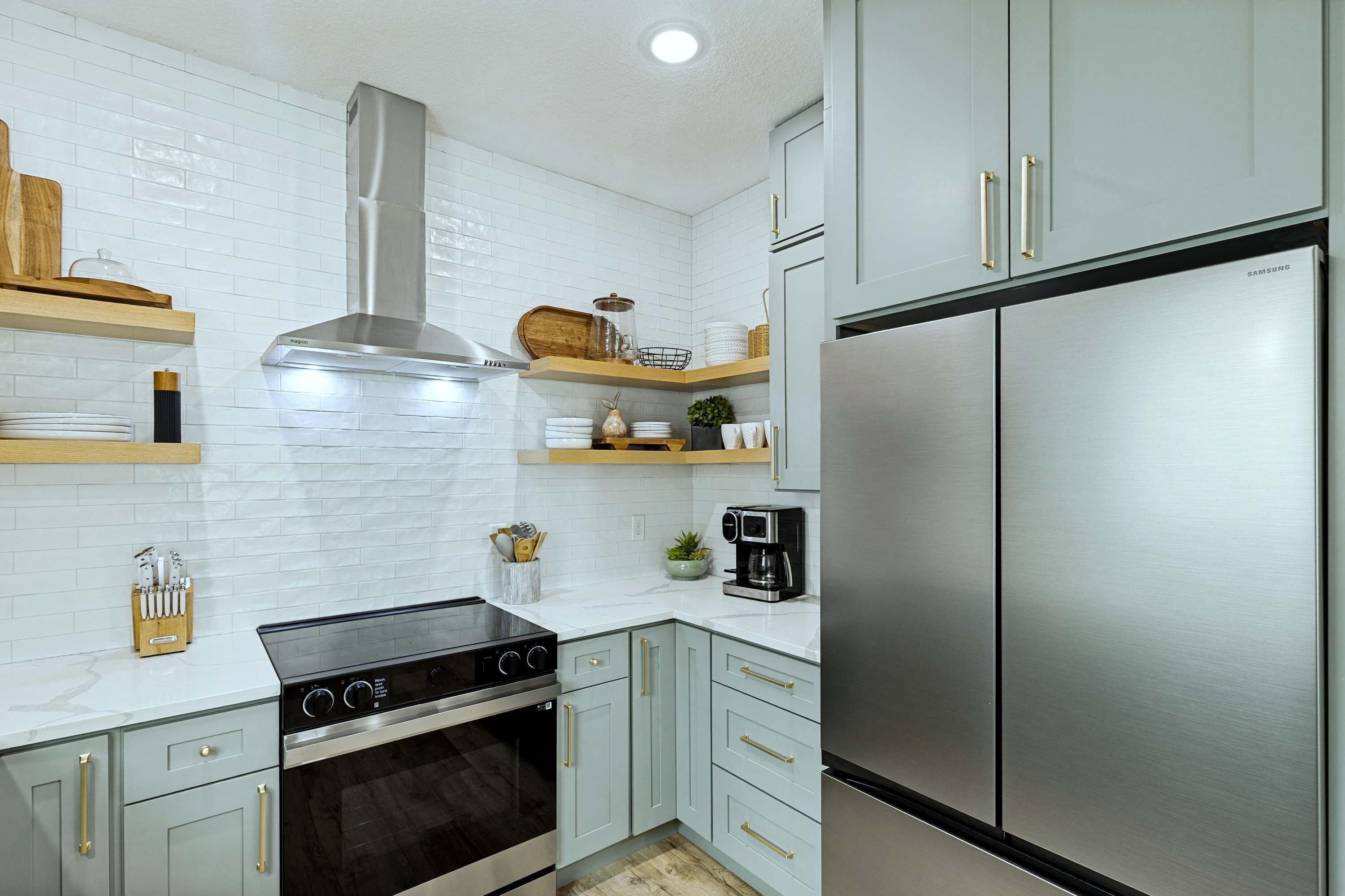 Une cuisine moderne avec des carreaux de céramique blancs disposés en motif métro, des appareils en acier inoxydable et des meubles de couleur bleu clair.