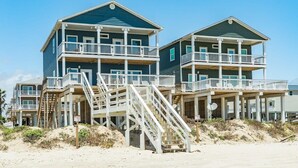 Une propriété située en bord de mer, dotée de plusieurs balcons et d’un escalier menant aux étages supérieurs.