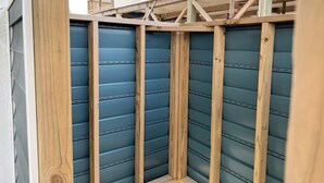 Un coin d’un bâtiment à la structure en bois, avec un mur extérieur bleu.