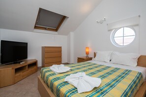 Une chambre à coucher avec un lit, une télévision, une fenêtre et une lampe.