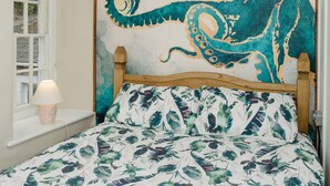 Un dormitorio con una cama, una ventana con vistas a la vegetación y una pared con un mural grande de pulpo.