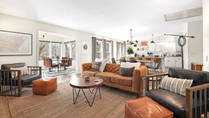 Ein geräumiges Wohnzimmer mit einer großen Couch, einem Couchtisch und einem Essbereich mit Stühlen und einem Tisch.