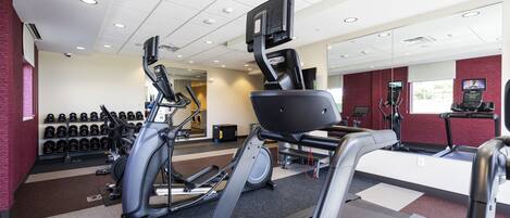 Une salle de sport équipée de tapis de course, de vélos elliptiques et de matériel de musculation.