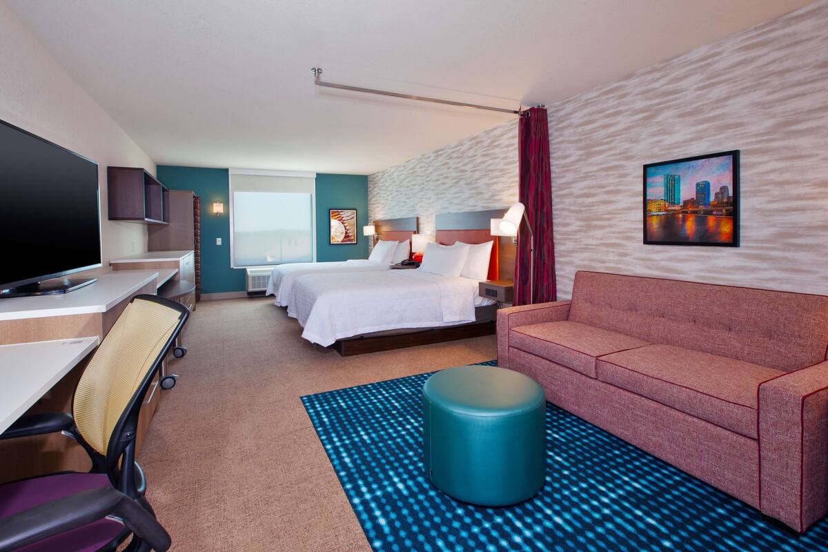 Une chambre d’hôtel comprenant un lit, un canapé, une télévision, un bureau et une salle de bain.
