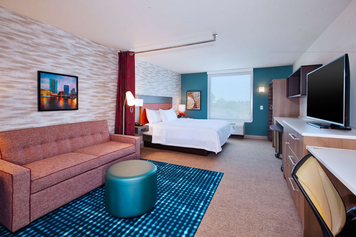 Une chambre d’hôtel moderne équipée d’un lit, d’un canapé, d’une télévision et d’un bureau.