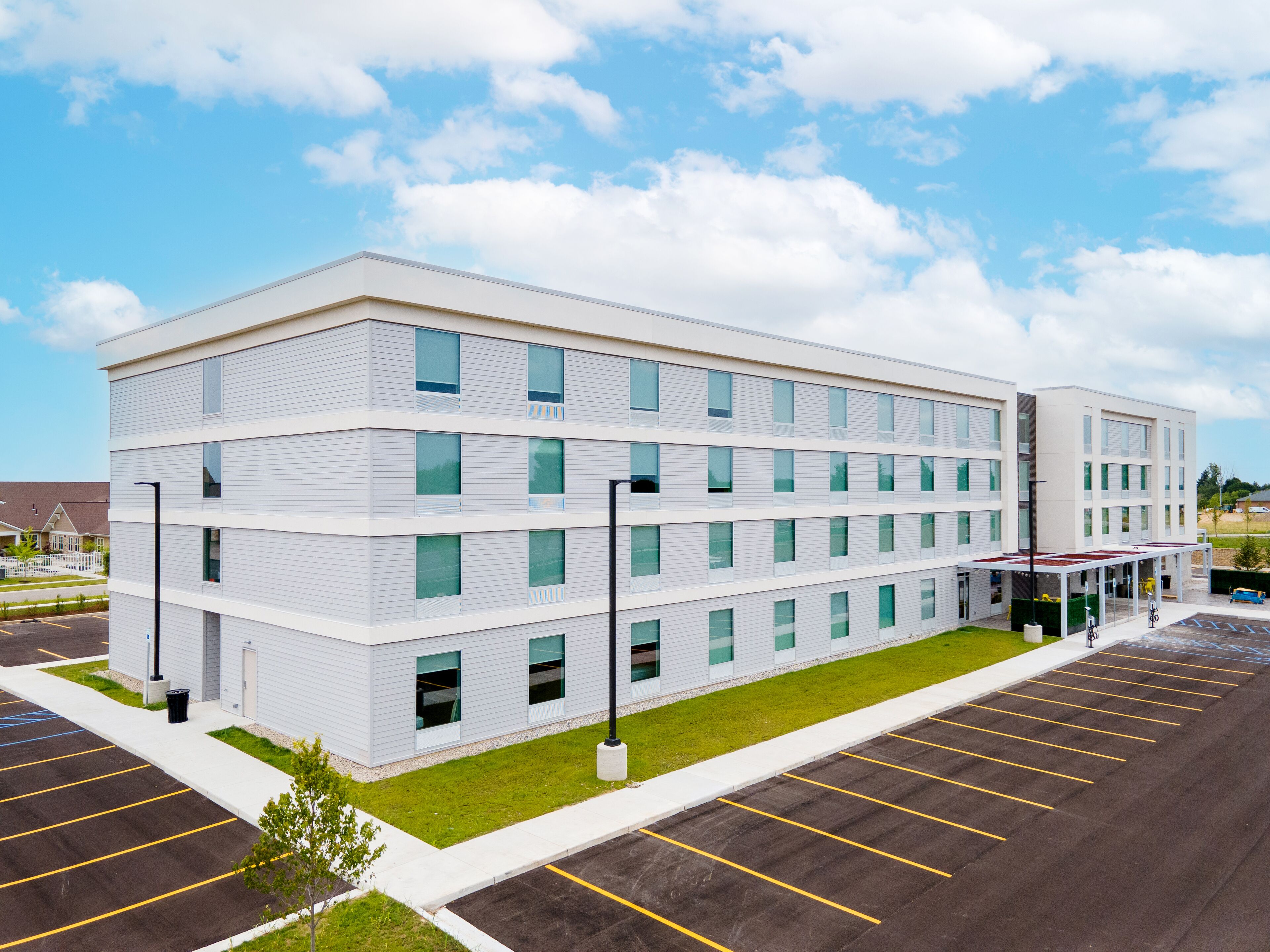 A multi-story building with a flat roof, large windows, and a covered entrance area.