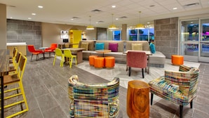 Een moderne lounge met zithoeken, inclusief banken en stoelen, en een eethoek met tafels en stoelen.