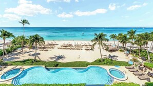 A resort with a large pool, beach area, and ocean view. - Beachcomber 21 by Grand Cayman Villas (7 Mile Beach)