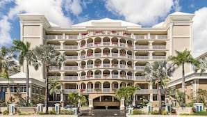 A multi-story hotel with a symmetrical facade, multiple balconies, and a central entrance. - Beachcomber 21 by Grand Cayman Villas (7 Mile Beach)