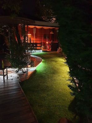 Une maison dotée d’une terrasse bien visible, d’une pelouse bien entretenue et d’un bâtiment à l’extérieur rouge.
