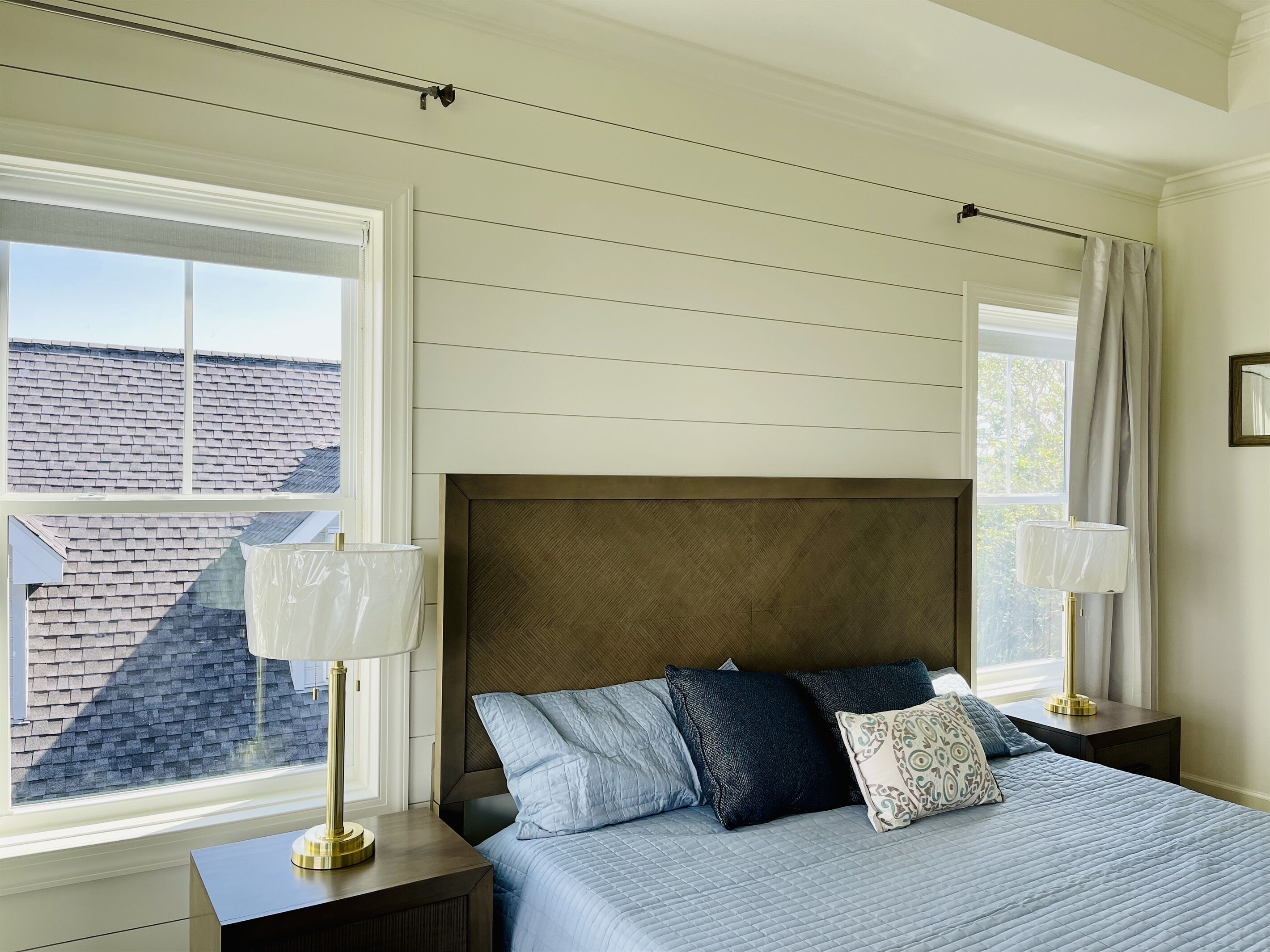 Une chambre à coucher avec un lit, des tables de chevet, une fenêtre et une vue sur le toit.