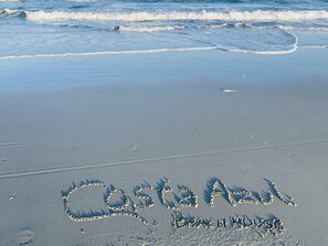 A beach with the words "Costa Azul Beach House" written in the sand.