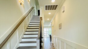 Un escalier avec des marches en bois et une rampe, menant à un palier doté d’une porte.