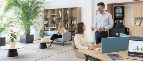 A modern office space with a coffee machine, bookshelves, and comfortable seating areas.