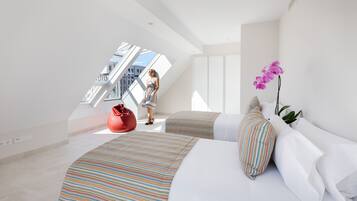 Un dormitorio moderno con una cama curvada, un ventanal grande y un sillón de peluche rojo.