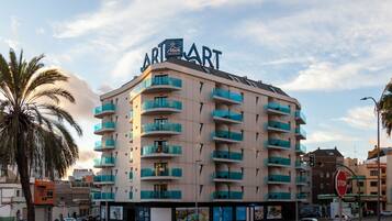A multi-story hotel with balconies, a stop sign, and a palm tree.