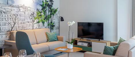 Ein modernes Wohnzimmer mit einer Couch, einem Couchtisch und einem Flachbildfernseher.