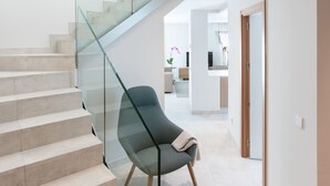 A modern interior with a glass staircase, a seating area, and a kitchen in the background. - ART en Las Palmas - Viviendas Vacacionales (Las Palmas de Gran Canaria)