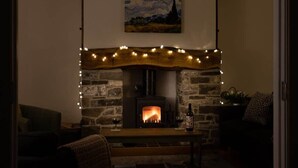 A cozy living room with a stone fireplace, a hanging light fixture, and a painting on the wall. - Brecon Beacons Retreat | 2 Cottages | Hot tub (Myddfai, Llandovery)