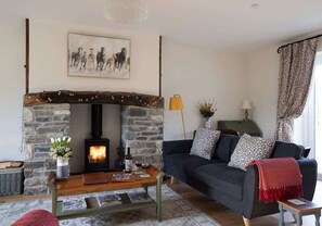 A cozy living room with a stone fireplace, a sofa, a coffee table, and a painting on the wall.