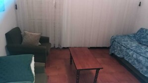A living room with a green armchair, a blue sofa, and a wooden coffee table. - Sestino, Sasso di Simone Natural Park (Sestino)