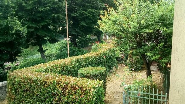A landscaped garden with neatly trimmed hedges, a paved walkway, and a metal gate. - Sestino, Sasso di Simone Natural Park (Sestino)
