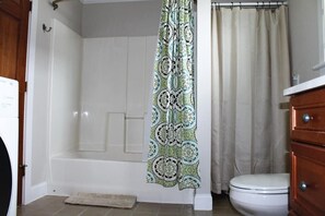 A bathroom with a bathtub, toilet, and a shower curtain. - Modern Condo #1! (Ellsworth)