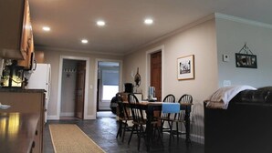 A dining area with a table and chairs, a kitchen area with cabinets and appliances, and a living room with a couch. - Modern Condo #1! (Ellsworth)