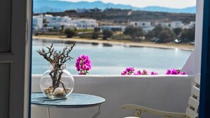 A balcony with a glass table, a vase with branches and pebbles, and purple flowers. - Beachfront Bocamviglies Room/Naoussa Cycladic Nest (Naoussa)