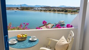 A balcony with a table set for two, overlooking a calm body of water with a boat and buildings in the distance. - Beachfront Bocamviglies Room/Naoussa Cycladic Nest (Naoussa)